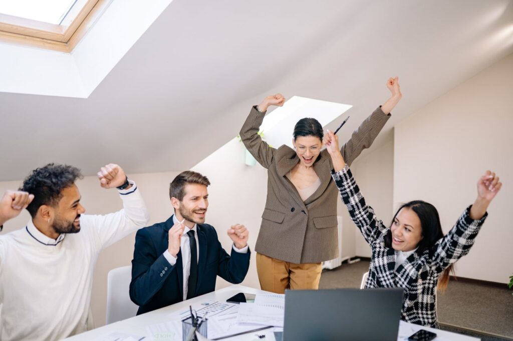 Diverse group of professionals celebrate a team success in a contemporary office setting.